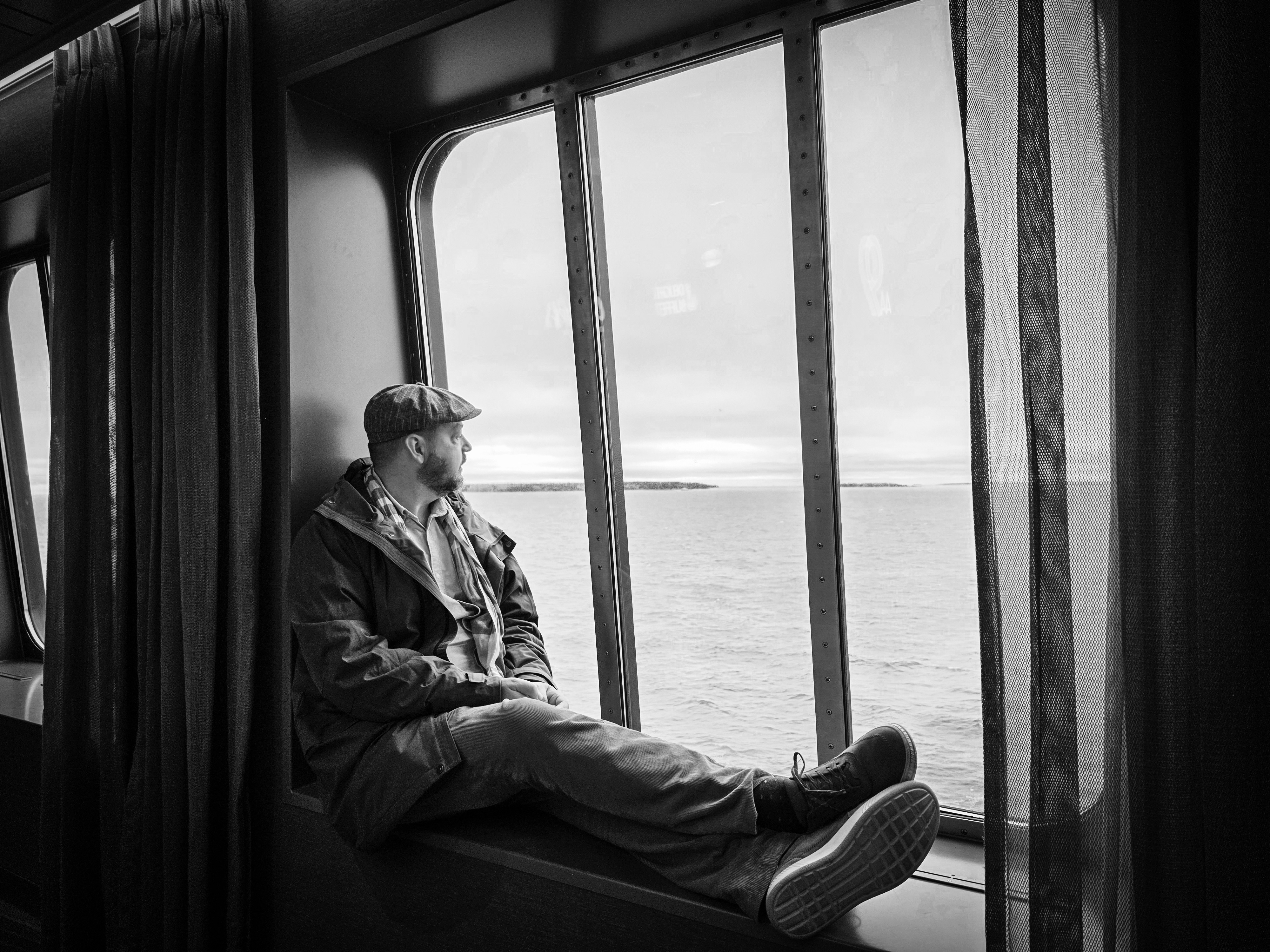 Marius sitting by a ferry window, looking out over the sea