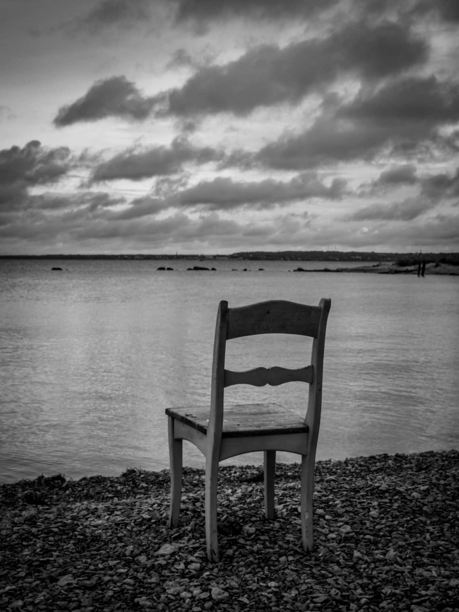 An empty chair by the sea, black and white photograph