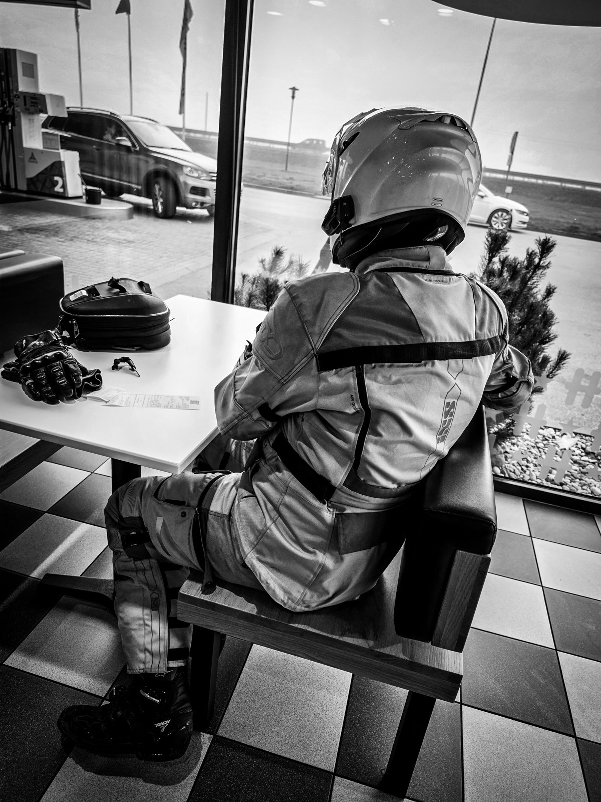 Motorcyclist in protective gear seated at a roadside restaurant
